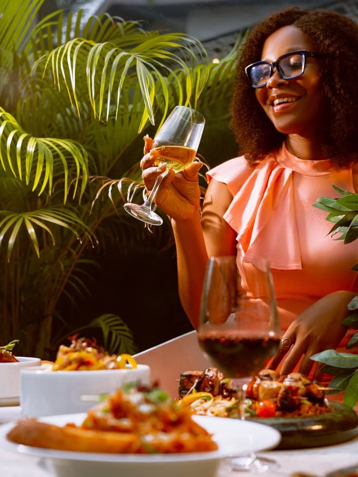 A woman enjoying a relaxed meal alone beside tropical greenery